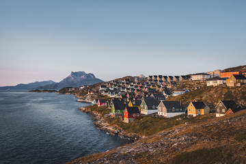 Fototapeta na wymiar Nuuk capital of Greenland with Beautiful small colorful houses in myggedalen during Sunset Sunrise Midnight Sun. Sermitsiaq Mountain in Background. Blue and pink Sky.