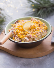 Salad with tuna, corn, onion, raw carrot, eggs, in   gray plate on a light concrete background. New Year salad recipes. Top view.