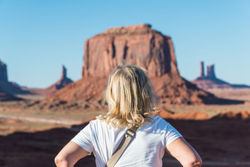 A blonde and mature woman stands by The Merrick Butte in Monument Valley, Navajo Land, AZ