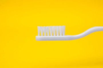 White toothbrush on yellow background. Space for text