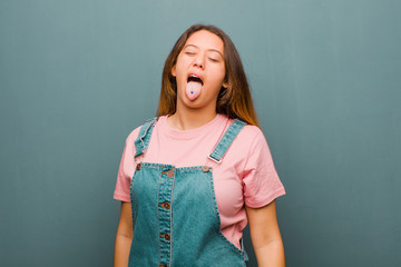 young pretty latin woman with cheerful, carefree, rebellious attitude, joking and sticking tongue...