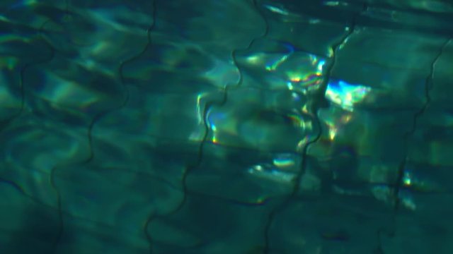 Close up of slow motion waves over deep water in night swimming pool.