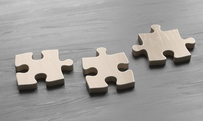 Obraz premium Disconnected pieces of wooden puzzle on black wooden background. 3d illustration