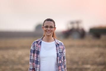 Farmer girl in front of tractor in field