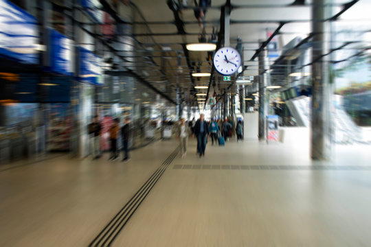 Blurry motion image of people walking at the main train station called Amsterdam Centraal. A major international railway hub, it is used by 162,000 passengers a day. Transportation concept.