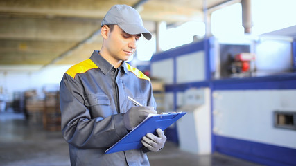 Pensive industrial worker writing on a document