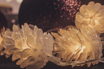 Decorative glowing cones with Christmas balls on background. Christmas toys of different colors with a garland in the form of cones for the Christmas tree