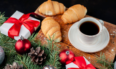 Christmas coffee and croissants with Christmas tree and gifts, toys on a stone background
