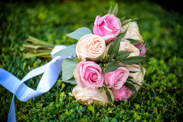 Wedding bouquet of yellow and white roses and blue fresia lying on wooden floor