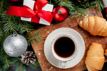Obraz na płótnie Canvas Christmas coffee and croissants with Christmas tree and gifts, toys on a stone background