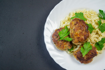 boiled pasta with meatballs on a white plate on a wooden board