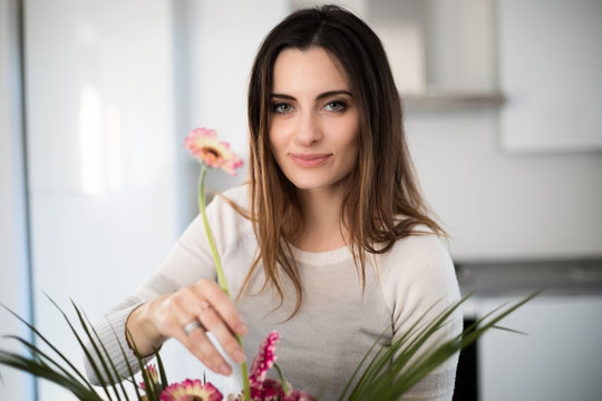 Young Woman Putting Colorful Flowers In Vase
