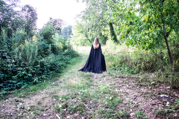A Girl in a black cape on the nature.  A girl in a hood. Danger.Fantasy
