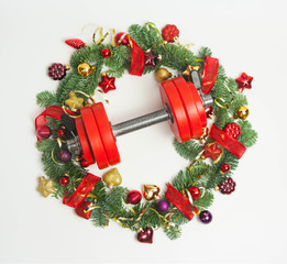 Christmas or New Year on a white background. Composition with dumbbells, gift, red and gold glass balls, fir tree branches for healthy lifestyle and sport