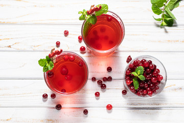Fresh vitamin tea with cranberry and mint on white rustic table top view. natural drinks for healthy lifestyle. Traditional autumn and winter tea.