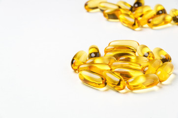 Group of yellow vitamin capsules on white background. Selective focus.