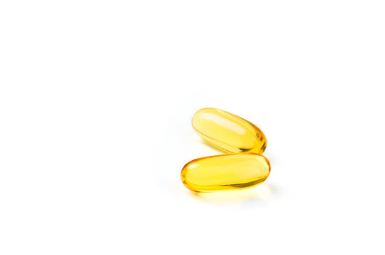 Pair of oil vitamin capsules on white background