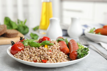Tasty buckwheat porridge with sausages on light grey marble table indoors. Space for text