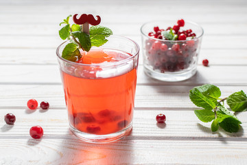 A glass of organic homemade cranberry tea with mint on the table close up. Traditional winter vitamin tea for flu and cold prophylaxis. 