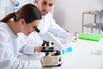 Scientist with microscope and colleague in laboratory. Medical research