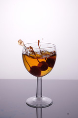 cocktail in a glass with cherries, splash