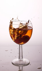 cocktail in a glass with cherries, splash