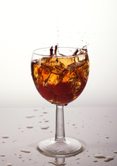 cocktail in a glass with cherries, splash