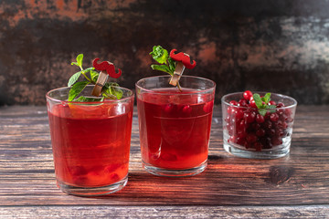 Two glasses of natural homemade non alcoholic cocktail with cranberries and mint on dark vintage background. Healthy vitamin drink.