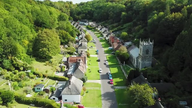 Quiet little town street with houses on both sides between a forest - tracking aerial shot