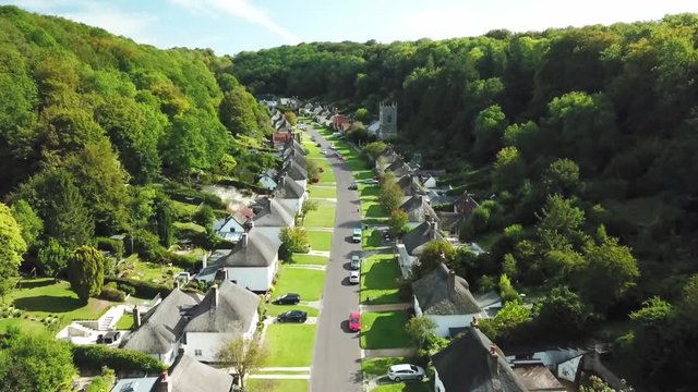 Quiet little town street with houses on both sides between a forest - fly through