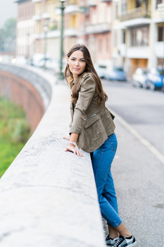 Young brunette woman looking at camera and leaning on a wall