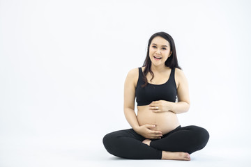 pregnancy, rest, people and expectation concept - happy pregnant woman sitting on bed and touching her belly at home