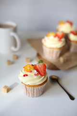 cupcake with cream cheese decorated with strawberries on a white background.