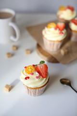cupcake with cream cheese decorated with strawberries on a white background.