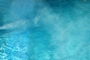 Pure clear water in the thermal pool. Hot water flows and fog rises above the pool, steam. Blue water, beautiful background. - obrazy, fototapety, plakaty