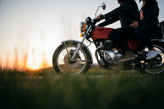 Crop shot of couple on vintage motorbike at sunset