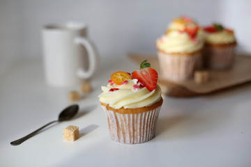 cupcake with cream cheese decorated with strawberries on a white background.
