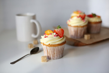 cupcake with cream cheese decorated with strawberries on a white background.