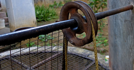 a rope on a iron made pully or wheel used to fetch  water from a deep well in India close up.
