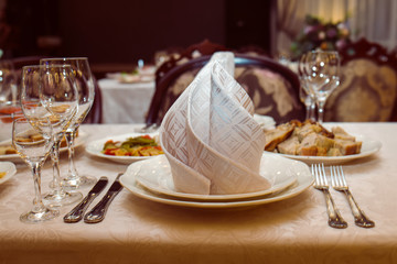 Close up of wedding table served with cutlery, serviette, crockery and  covered with a white tablecloth. Table served for wedding banquet in restaurant. Banquet. Wedding decoration.