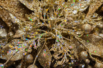 Close-up of a Golden shiny with shimmering and glowing colored lights sequins flower with berries-a festive Christmas decoration. Glamorous spectacular background. Selective focus
