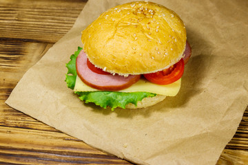 Fresh delicious homemade cheeseburger on brown paper on wooden table