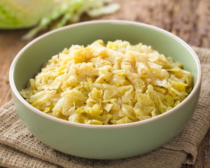 Fresh homemade braised white cabbage in bowl, raw cabbage in the back (Selective Focus, Focus one...