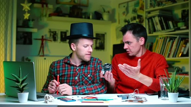 Photographers are sitting at the table and discussing the camera.  