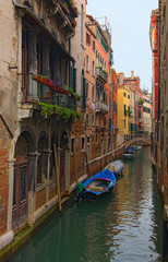 Fototapeta na wymiar Picturesque city landscape of Venice. Shaming narrow canal with turquoise water and moored boats near buildings. Romantic and peaceful scene. Venice, Italy