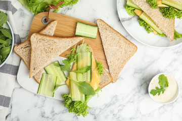 Flat lay composition with tasty sandwich and ingredients on white marble table