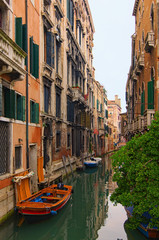 Romantic and peaceful scene of Venice city. Medieval buildings reflected in turquoise water. Boats moored along the buildings. Famous touristic place and romantic travel destination. Venice, Italy