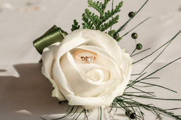 Close-up picture of wedding boutonniere with wedding ring. Wedding accessories bride and groom
