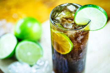 Cuba Libre cocktail with lime, ice, mint and tray on wooden table