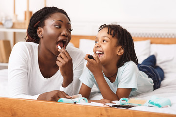 Black mom teaching daughter how to do makeup